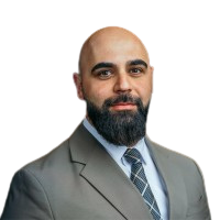 Headshot of a bald person with a dark beard wearing a gray suit and tie