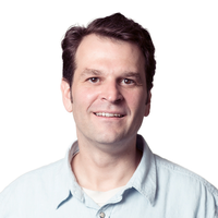 Headshot of a person with short brown hair wearing a light blue collared shirt, white background