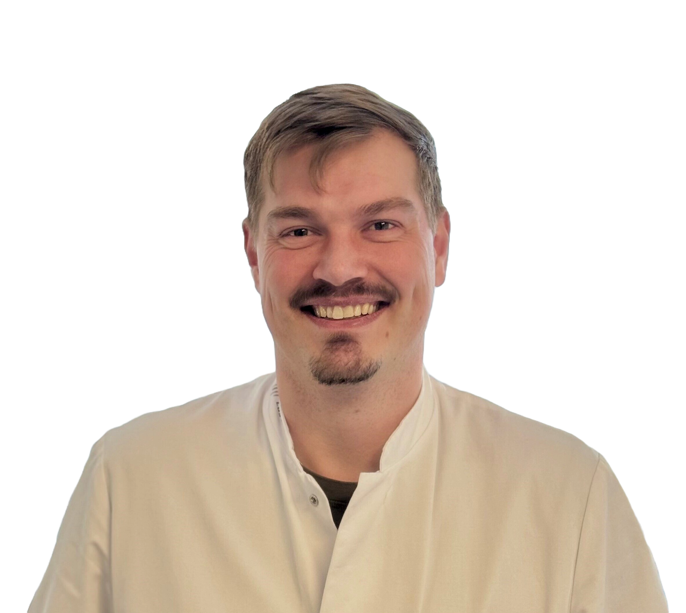 Smiling person with a mustache and goatee wearing a white medical coat