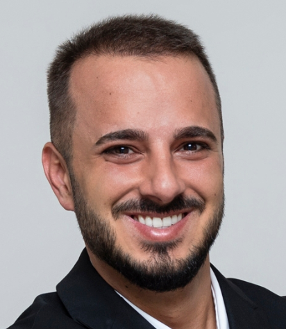 Headshot of David Prenka smiling, wearing a dark blazer, against a light gray background