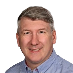 Headshot of a smiling person with gray hair wearing a light blue collared shirt, white background